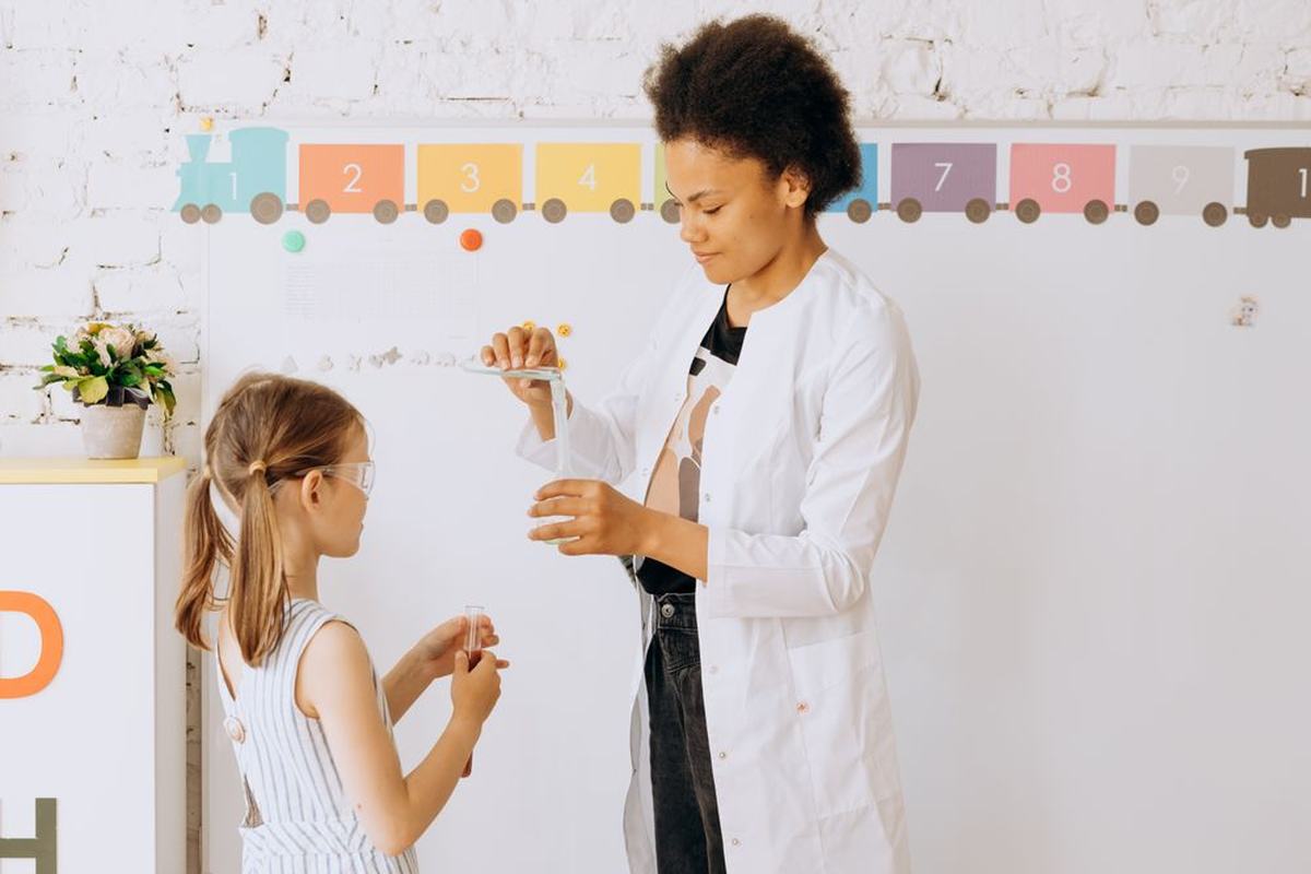 A teacher and a young student doing a science experiment together at a whiteboard